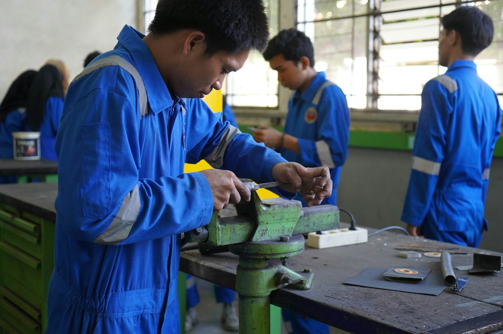Apprentices working on a piece of metal in a workshop